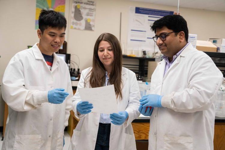 three students in white lab coat